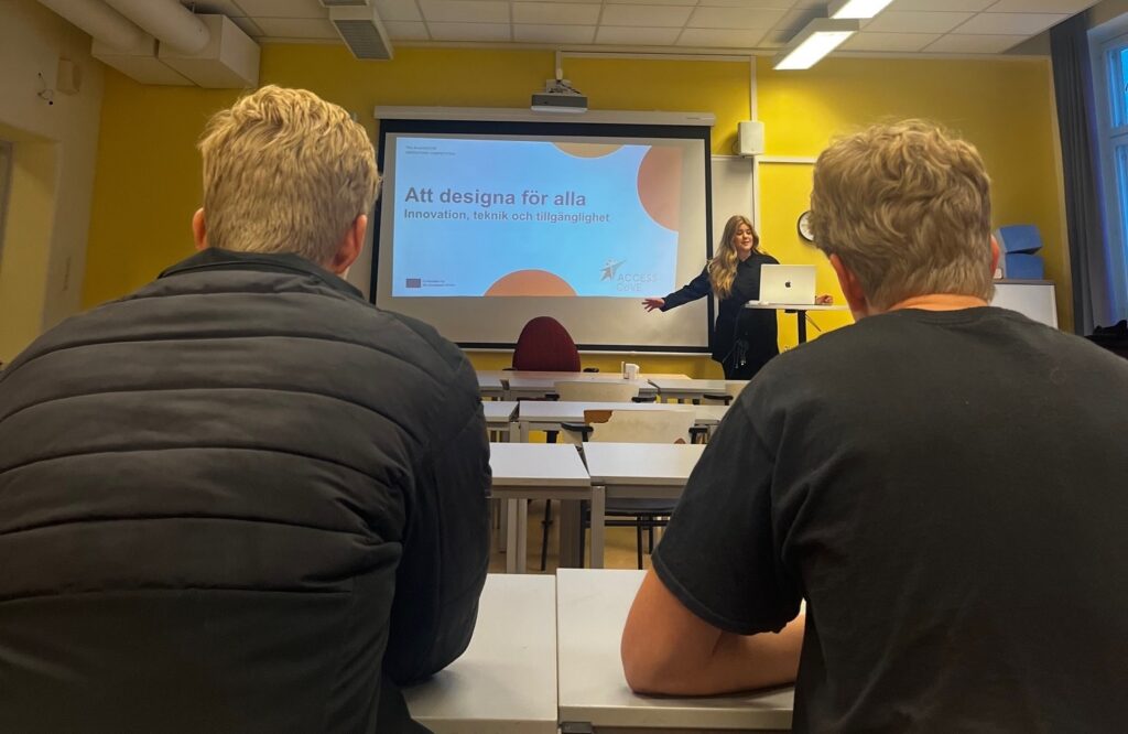 The image shows mentor Sofia Strömqvist from KTH presenting to high school students. She stands at the front of a classroom beside a laptop and projected slide stating the title of the presentation "designing for everyone", while students listen from their desks.
